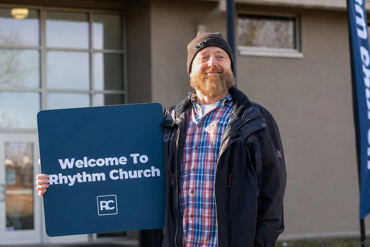 A Rhythm Church volunteer holding a welcome sign
