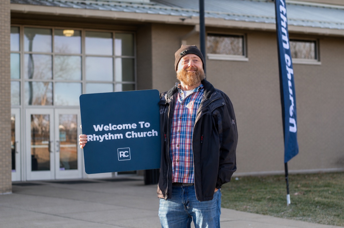 A Rhythm Church volunteer holding a welcome sign